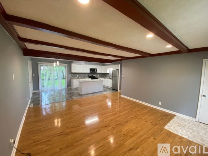 A spacious room with wooden flooring and a large window.