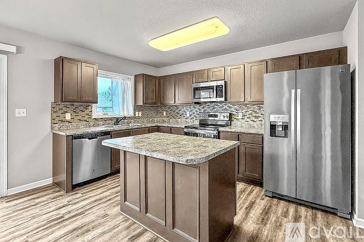 A kitchen with a granite countertop and stainless steel appliances.