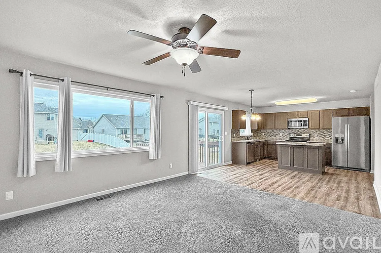 A spacious room with a ceiling fan and a view of the outside through the windows.