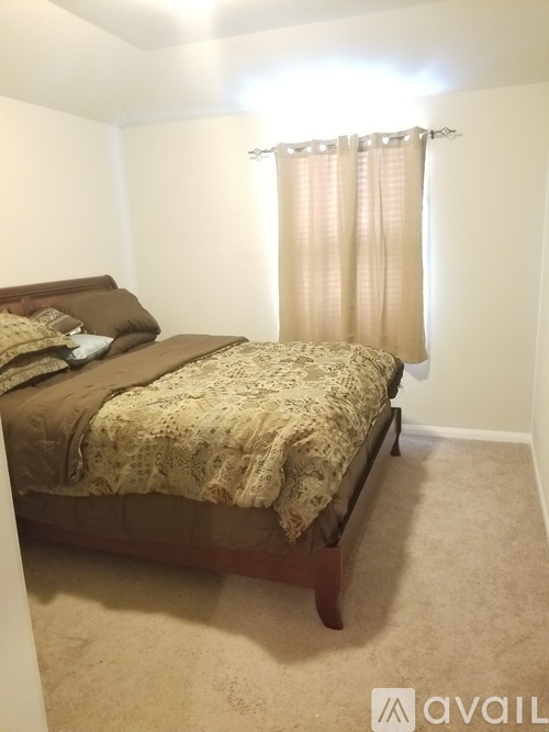 A bedroom with a bed and a window with curtains.