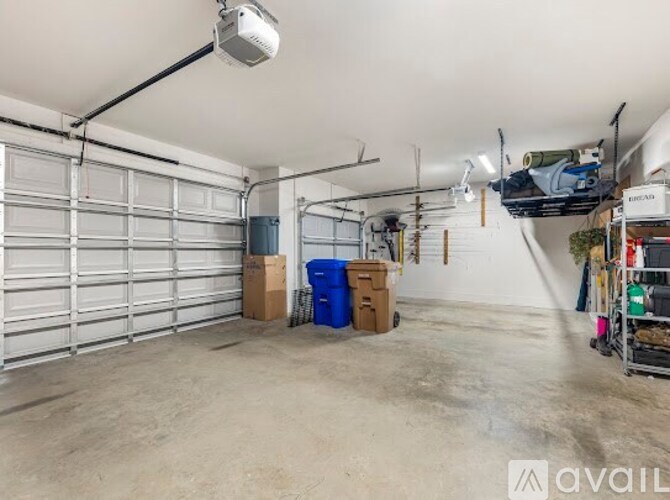 A spacious garage with a white ceiling and a large white garage door on the left.