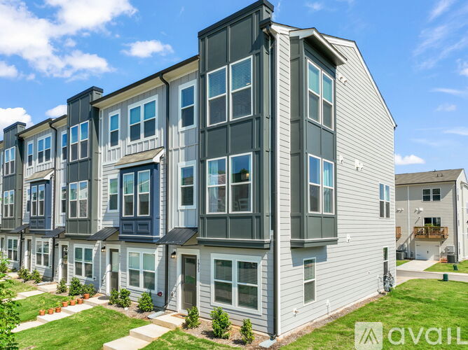 A row of modern townhouses with a grassy front yard.