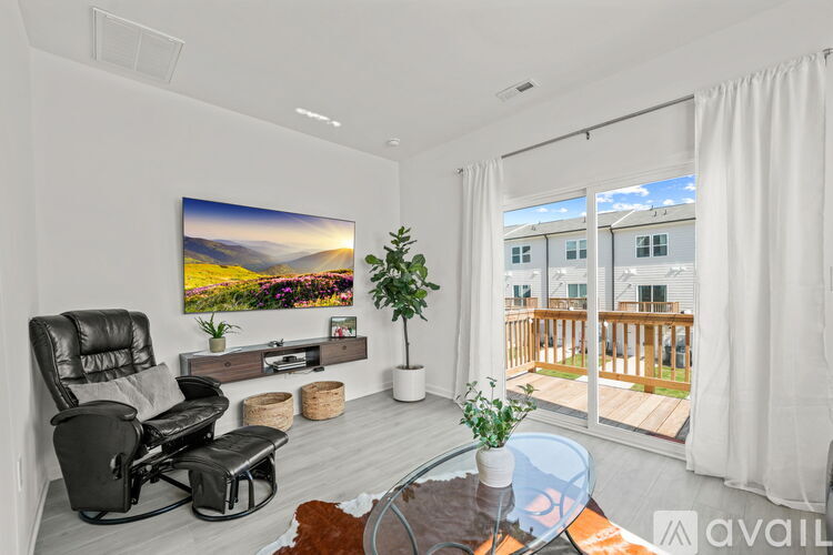 A modern living room with a black leather chair and a large painting of a landscape on the wall.