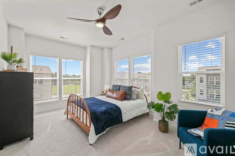 A bedroom with a bed, a fan, and a chair.