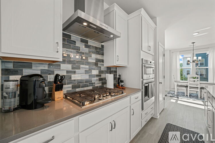A kitchen with white cabinets and a black coffee maker.