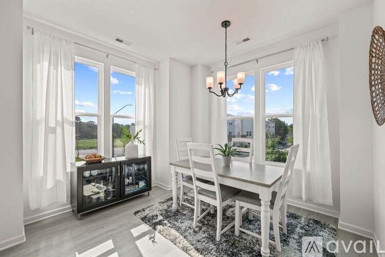 A dining room with a table and chairs and a view of the outdoors through the windows.