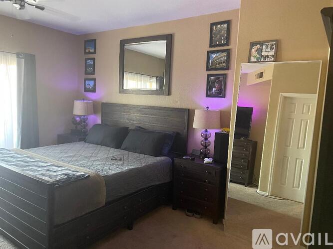 A bedroom with a large bed and a dresser with a mirror above it.