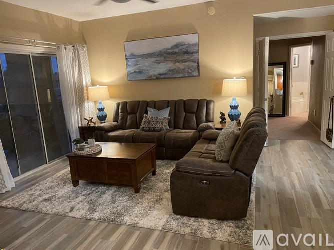 A living room with a brown sofa, a wooden coffee table, and a painting on the wall.