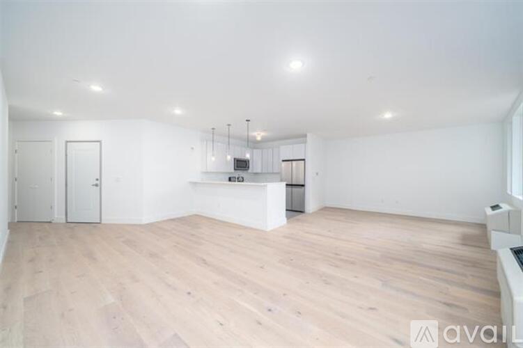 A spacious room with wooden flooring and white walls.