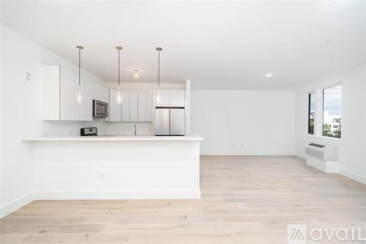 A spacious kitchen with white cabinets and a wooden floor.