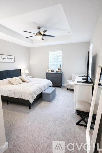 A bedroom with a bed, desk, and television.