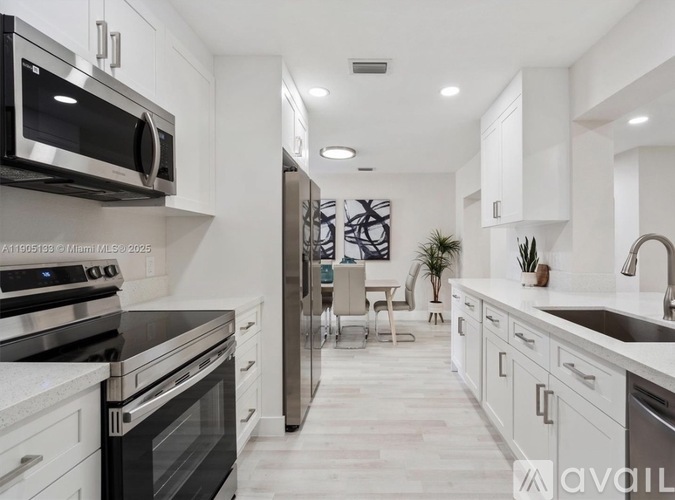 A modern kitchen with stainless steel appliances and white cabinets.