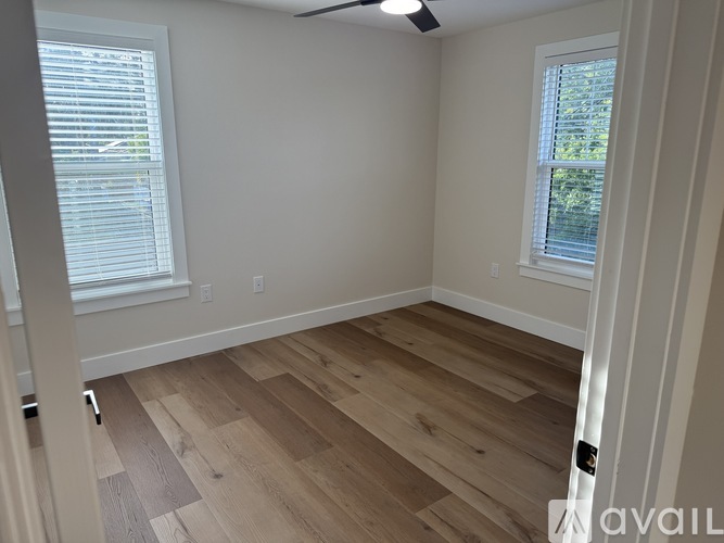 A room with wooden flooring and a window with blinds.