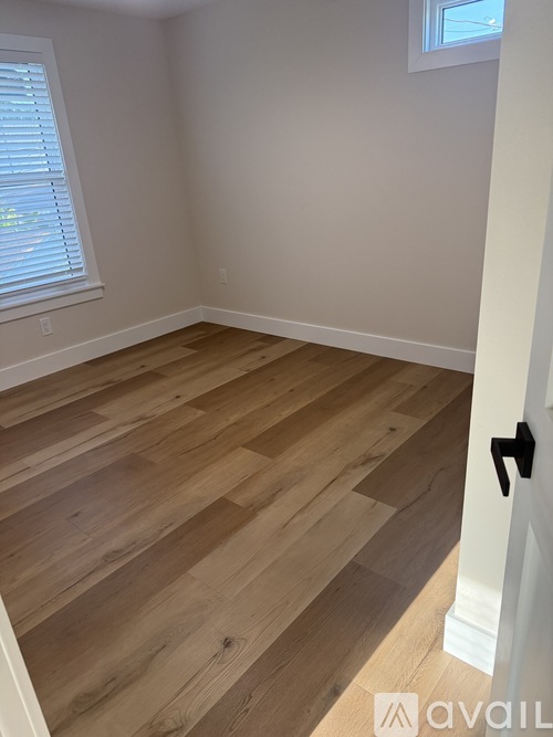 A room with wooden flooring and a black door handle.