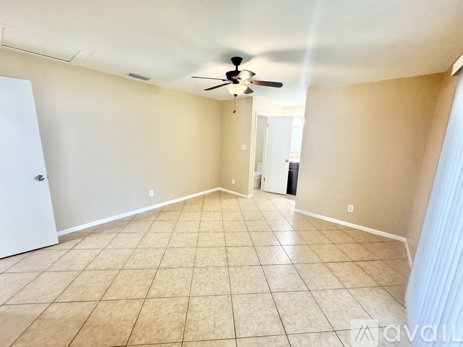 A spacious room with a ceiling fan and tiled floor.