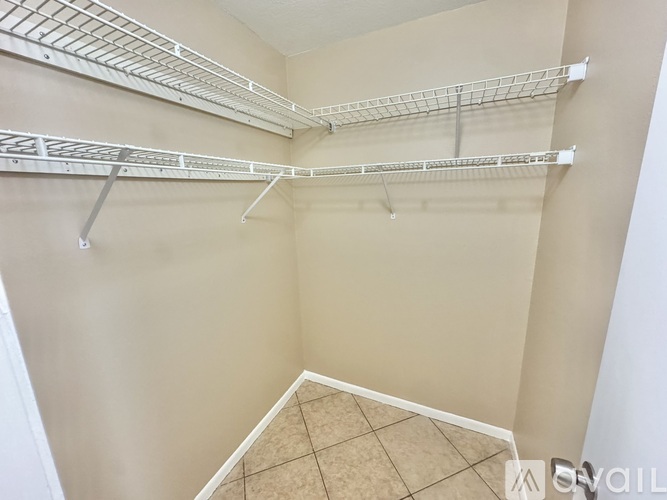 Empty walk-in closet with white shelving.