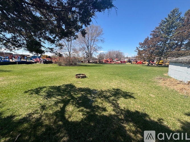 A grassy field with a tree and a metal pole in the foreground.