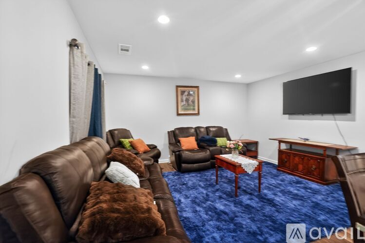 A living room with brown leather furniture and a blue carpet.