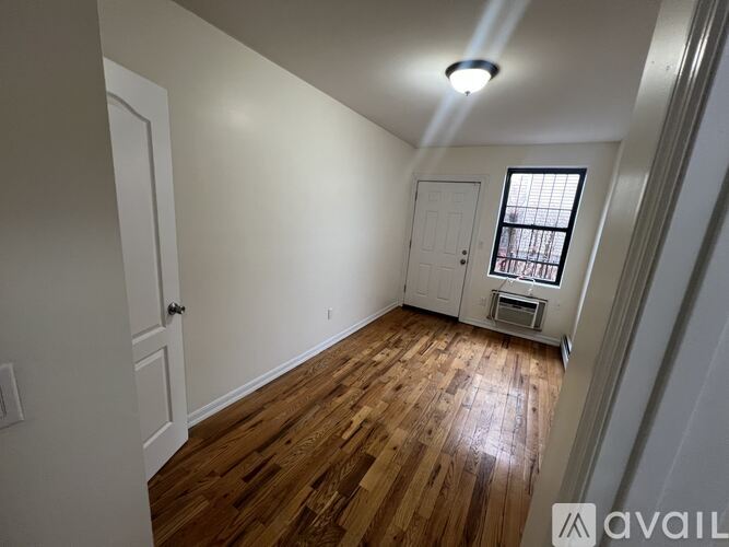 A room with wooden floors and a window with bars on it.