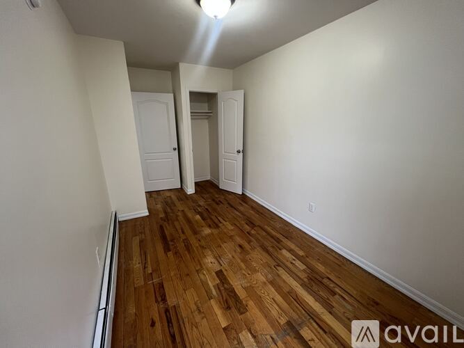 A room with wooden flooring and two doors.