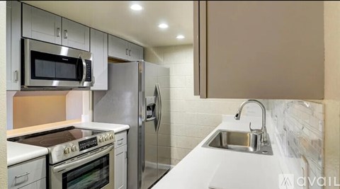 A modern kitchen with stainless steel appliances and white countertops.