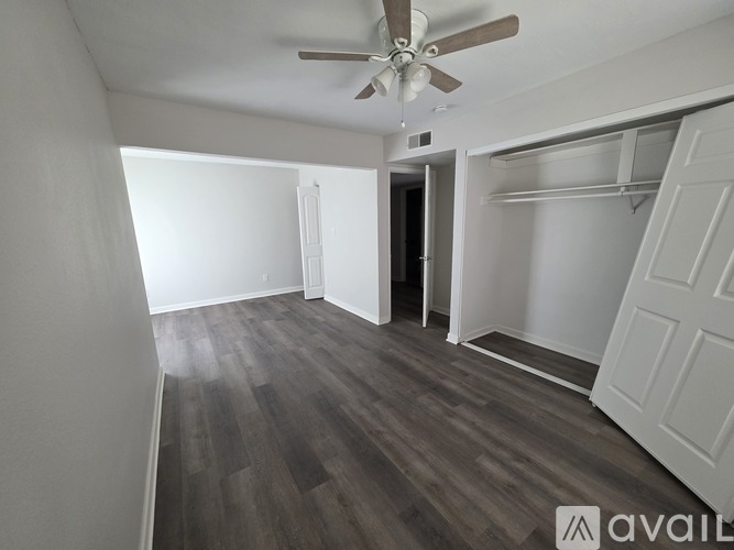 A room with a ceiling fan and wooden flooring.