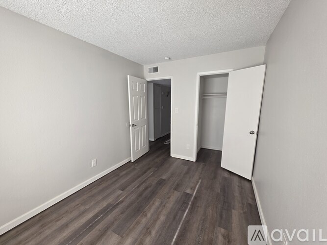 A room with wood flooring and white walls, with two doors and one open.