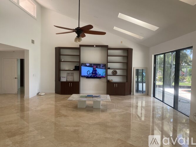 A spacious living room with a television and a ceiling fan.