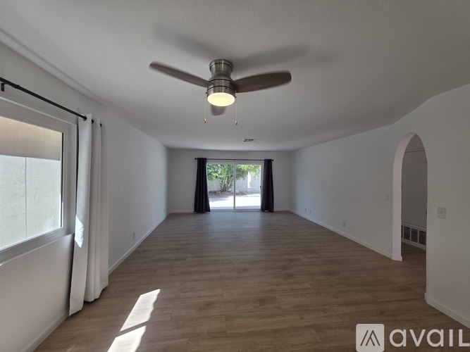 A spacious room with a ceiling fan and wooden flooring.