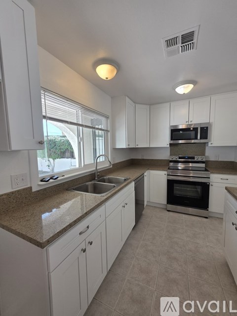 A kitchen with white cabinets and a granite countertop.