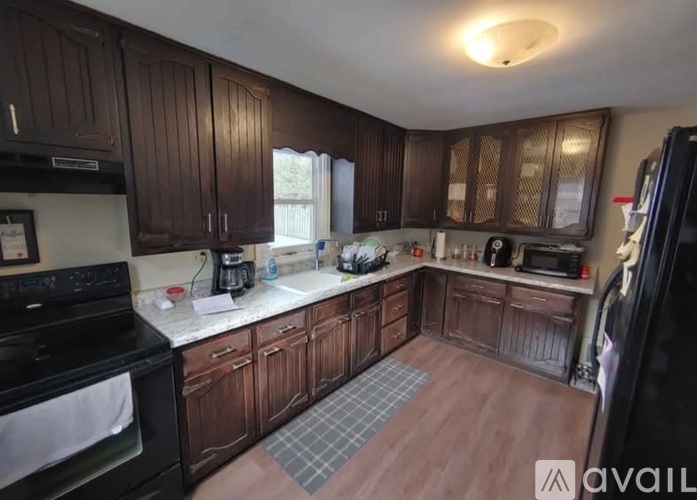A kitchen with dark wood cabinets and a black stove top oven.