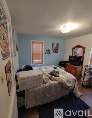 A bedroom with a bed, dresser, and television.