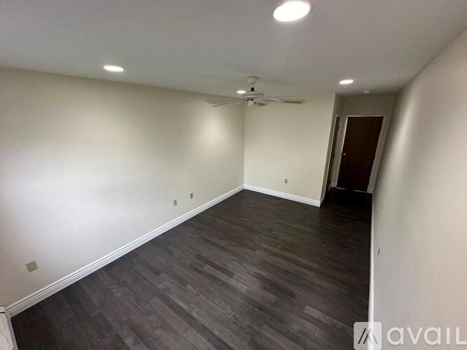 A room with a ceiling fan and wooden flooring.