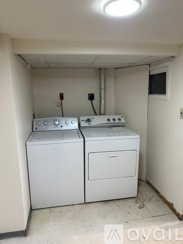 Two white front loading washing machines in a small room.