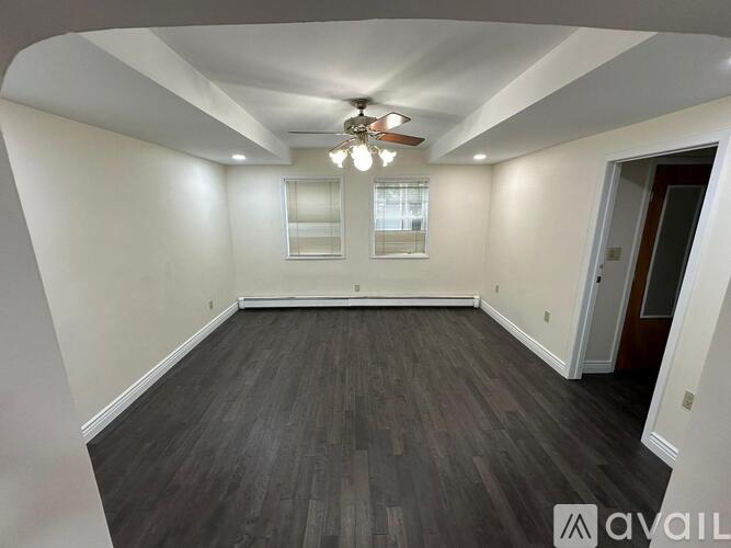 A room with a ceiling fan and a window with blinds.