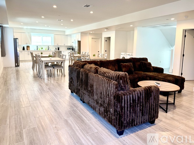 A living room with a brown couch and a dining table.