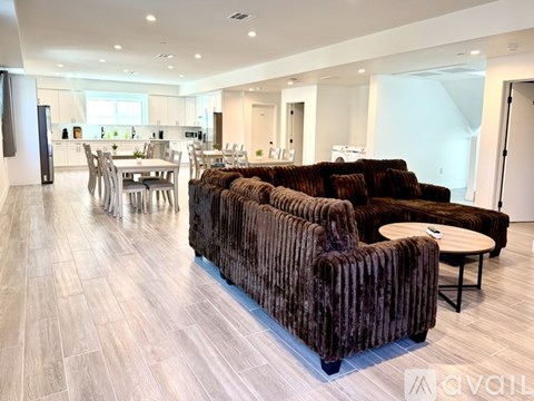 A living room with a brown couch and a dining table.