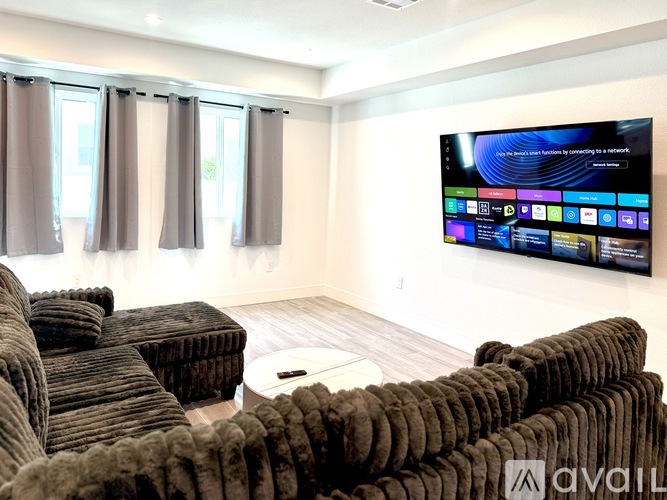A living room with a large screen TV mounted on the wall.