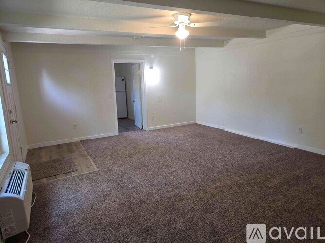 A carpeted room with a doorway leading to another room.