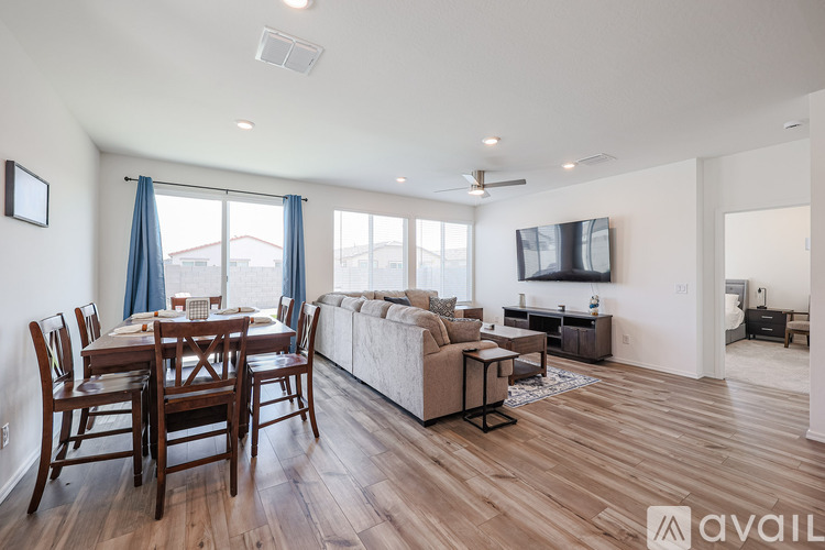 A living room with a wooden floor and a television mounted on the wall.