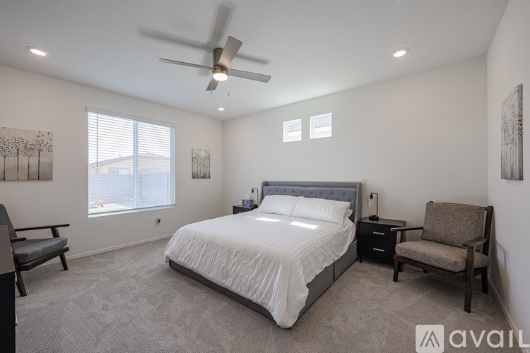 A bedroom with a bed, chair, and ceiling fan.