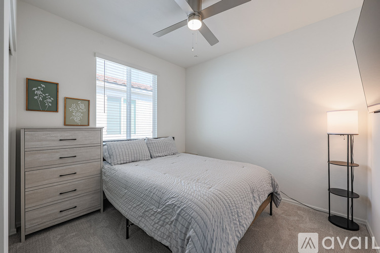 A bedroom with a bed, dresser, and a ceiling fan.