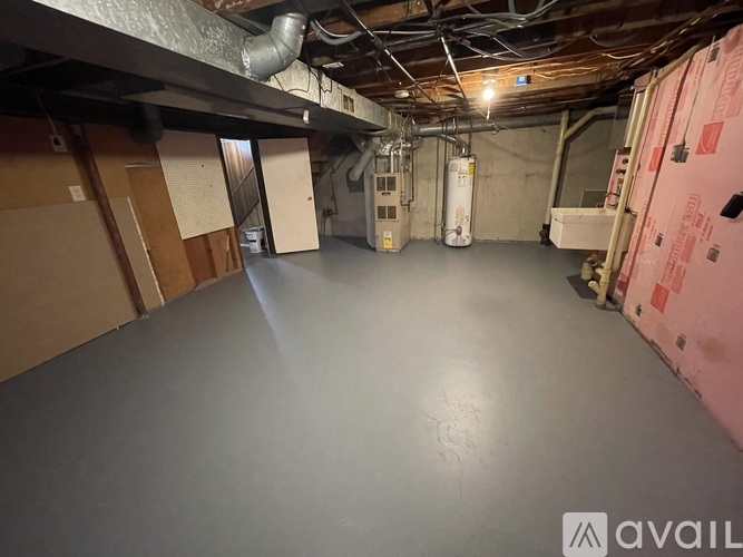A spacious unfinished basement with a grey floor and exposed ceiling beams.