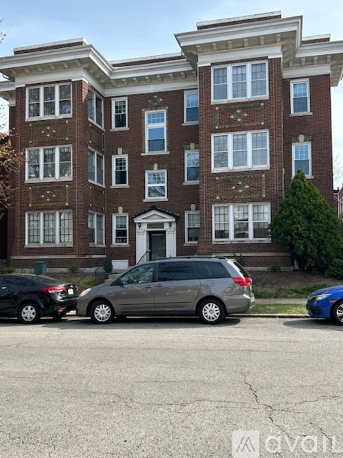 A silver minivan is parked in front of a red brick apartment building.