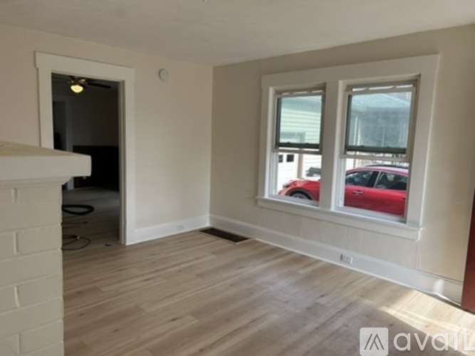 A room with a fireplace and a window overlooking a parking lot.