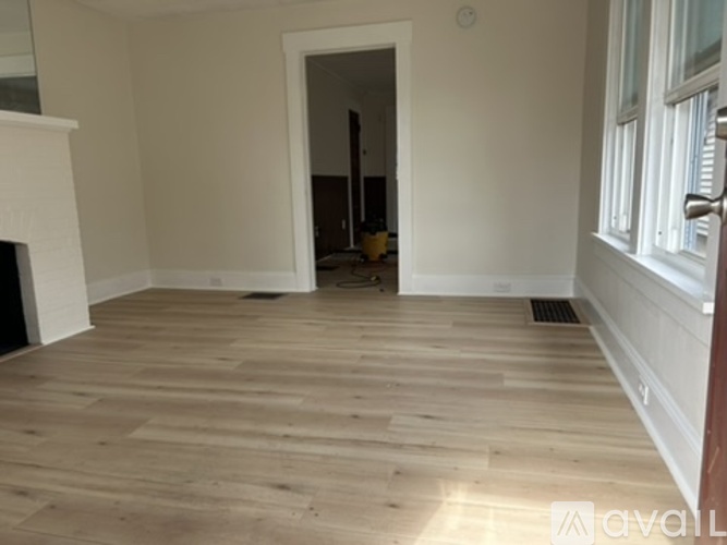 A room with wooden flooring and a fireplace.