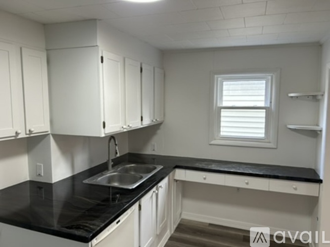 A kitchen with white cabinets and black countertops.
