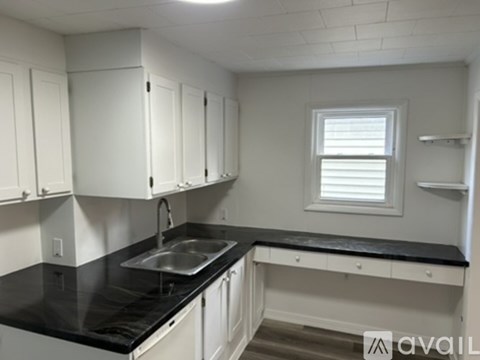 A kitchen with white cabinets and black countertops.