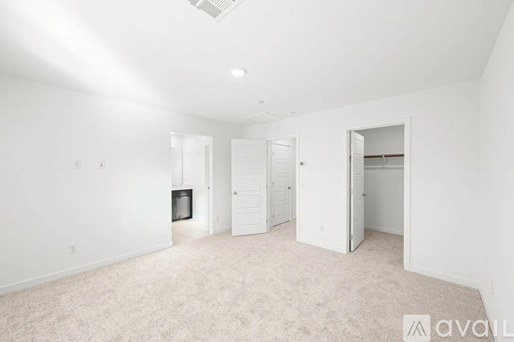 A spacious, empty room with white walls and carpeted floor.