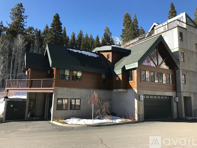 A large house with a balcony and a garage is surrounded by trees.
